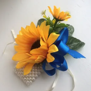 A wrist corsage featuring a yellow sunflowers on an ivory pearl bracelet